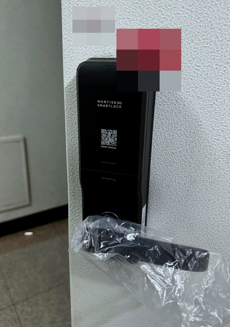 서해구 석남3동 출장 — 오돌토돌한 흰 문에 달린 길쭉한 검은 도어락 본체와 비닐 씌운 레버 손잡이
